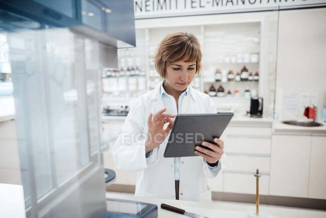 Farmacista femminile che utilizza tablet digitale mentre si trova in laboratorio — Foto stock