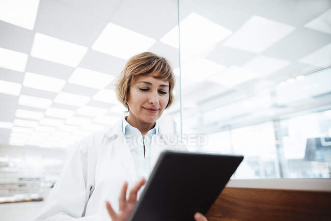 Sorridente professionista medico femminile utilizzando tablet digitale in farmacia — Foto stock