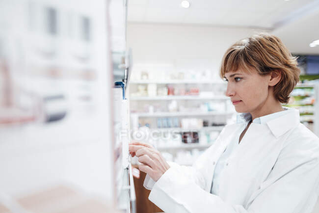 Farmacéutica mujer que busca medicina en farmacia - foto de stock