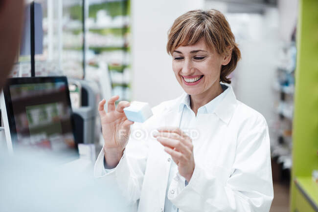 Sorridente farmacista femminile che spiega la medicina al cliente maschile presso il negozio di medicina — Foto stock