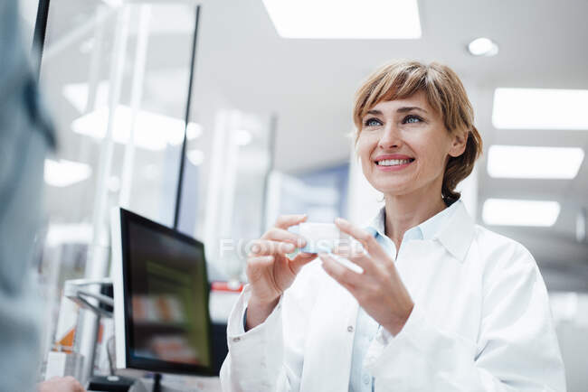 Sorridente farmacista femminile che discute di medicina con il cliente maschile presso il negozio di farmacia — Foto stock