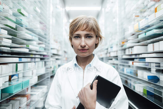 Chimica donna matura con tablet digitale in piedi in farmacia — Foto stock
