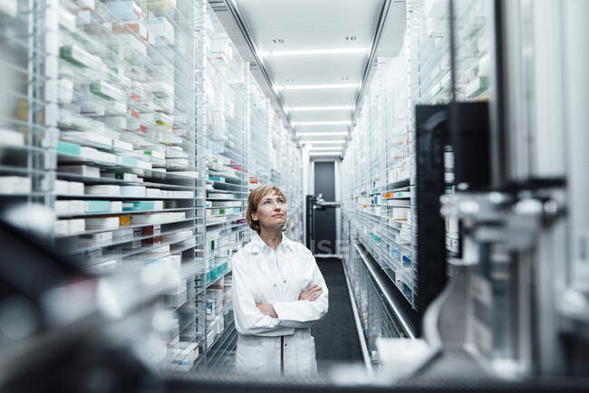 Farmacista donna con le braccia incrociate guardando la medicina in farmacia — Foto stock