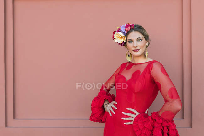 Female flamenco artist standing with hands on hips in front of red wall — Stock Photo
