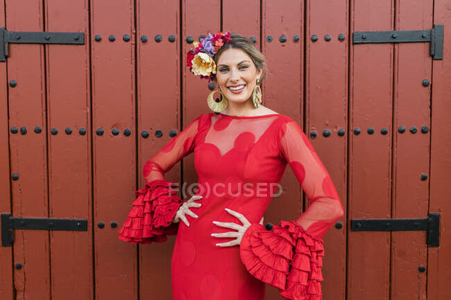 Smiling female flamenco dancer standing in front of red door — Stock Photo