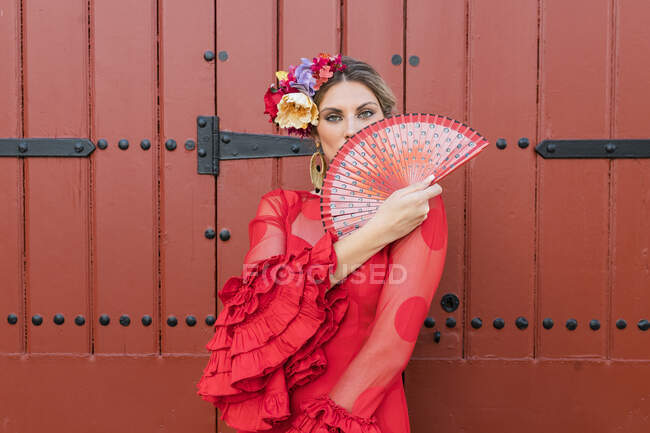 Female flamenco artist in traditional red dress holding hand fan — Stock Photo