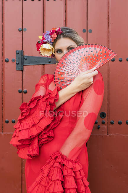 Female flamenco dancer looking through hand fan while standing in front of door — Stock Photo