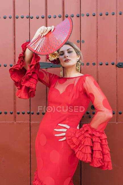 Confident female flamenco dancer holding hand fan in front of entrance — Stock Photo