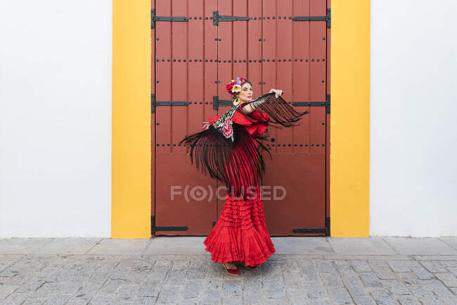 Female artist wearing flamenco dress and shawl dancing on footpath — Stock Photo