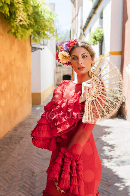 Жіночий художник з традиційним одягом і вентилятором стоїть на алеї. — стокове фото