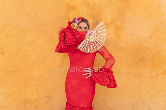 Ballerina che indossa abito tradizionale rosso in piedi davanti alla parete arancione — Foto stock