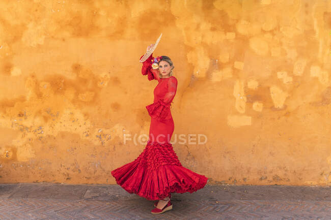 Female flamenco artist with hand fan dancing on footpath — Stock Photo
