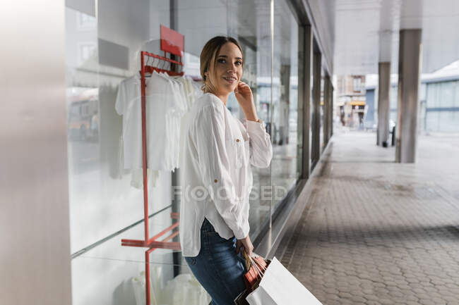 Sorridente giovane donna in piedi con borse della spesa sul sentiero — Foto stock