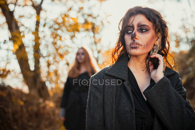 Mujer con maquillaje espeluznante en el bosque durante Halloween - foto de stock