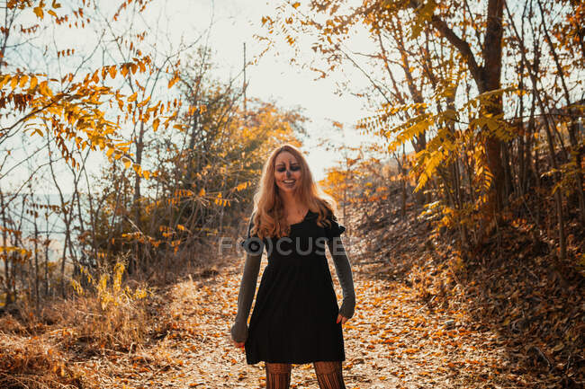 Lächelnde Frau mit Halloween-Make-up steht im Herbst im Wald — Stockfoto
