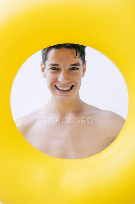 Sorrindo adolescente menino olhando através de flutuador de natação — Fotografia de Stock