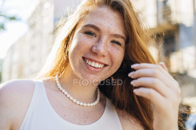 Happy young woman with freckles wearing pearl necklace — Stock Photo