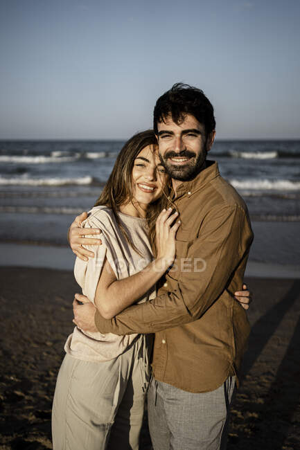 Smiling young couple embracing each other on beach — Stock Photo