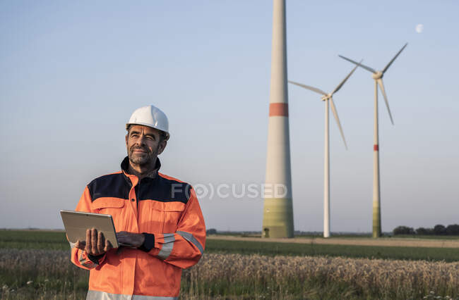 Thoughtful male engineer holding digital tablet at sunset — Stock Photo