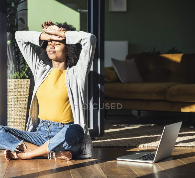 Femme avec les bras levés bronzer par ordinateur portable à la maison — Photo de stock