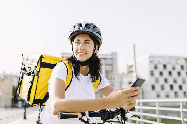 Mulher de parto sorridente com telefone móvel inclinado no punho da bicicleta — Fotografia de Stock