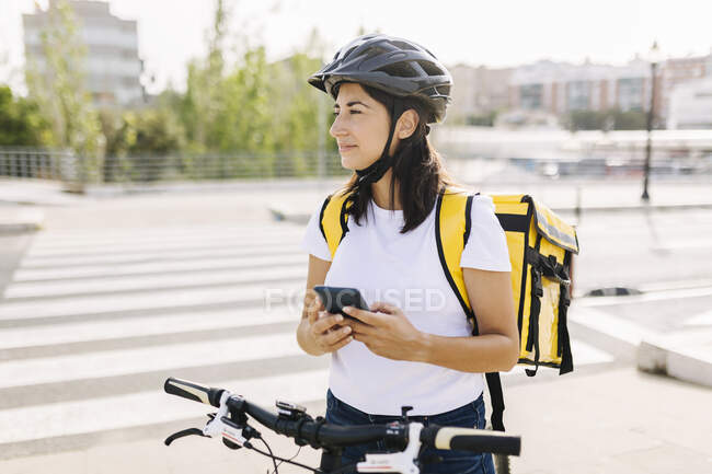 Mulher com saco de entrega e telefone celular em pé na estrada — Fotografia de Stock