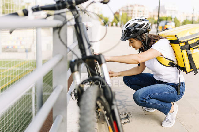 Mulher com entrega mochila reparação de bicicleta na estrada — Fotografia de Stock