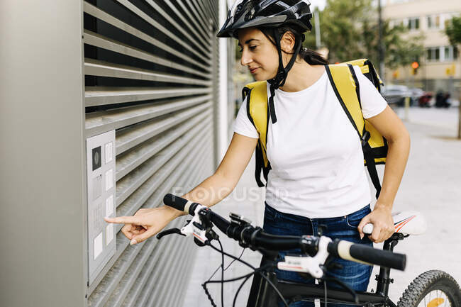 Mulher de entrega portão de abertura enquanto está de pé de bicicleta — Fotografia de Stock