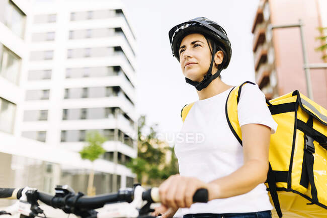 Pessoa de entrega feminina com mochila segurando alça de bicicleta — Fotografia de Stock