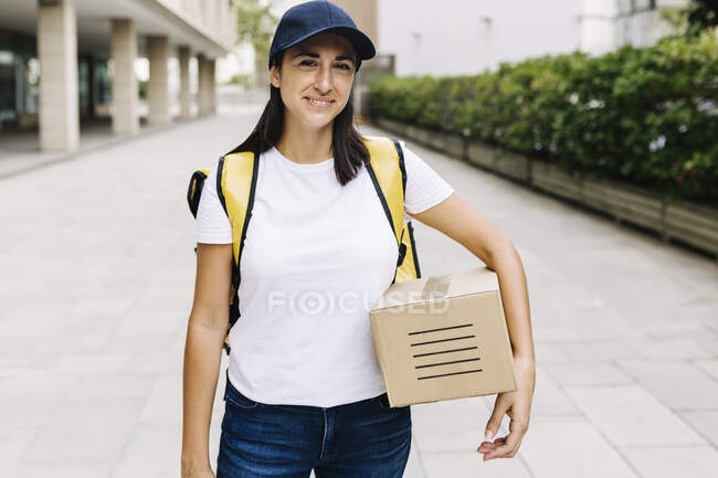 Mulher de entrega com caixa em pé no caminho — Fotografia de Stock