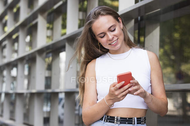 Blonde Geschäftsfrau lächelt, während sie ihr Handy benutzt — Stockfoto