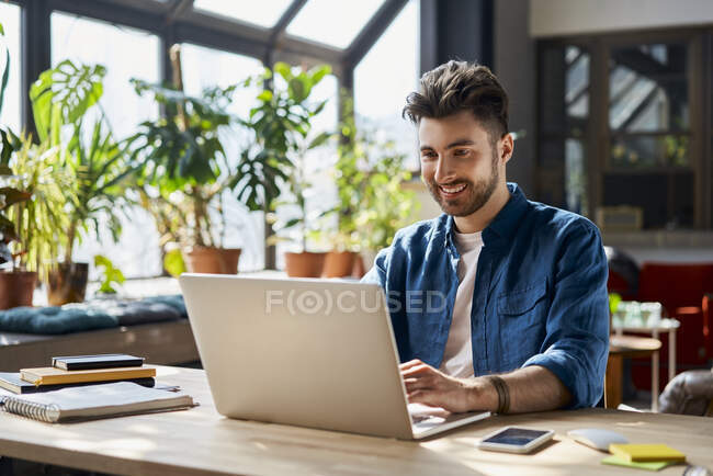 Professionista sorridente che lavora su computer portatile alla scrivania in ufficio — Foto stock