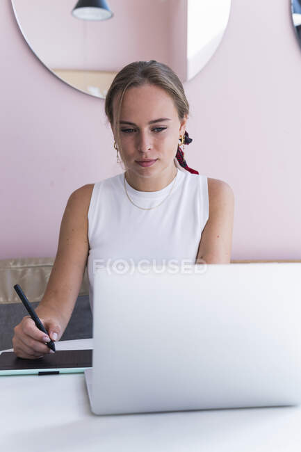 Junge Designerin sitzt mit Grafik-Tablet im Café — Stockfoto