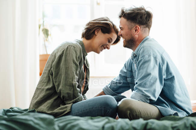 Joyeux couple adulte assis sur le lit à la maison — Photo de stock
