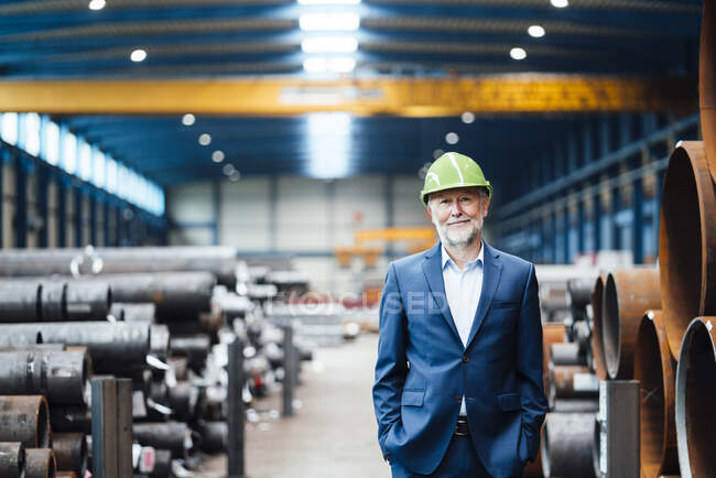 Directeur général souriant debout avec les mains dans les poches à l'entrepôt — Photo de stock