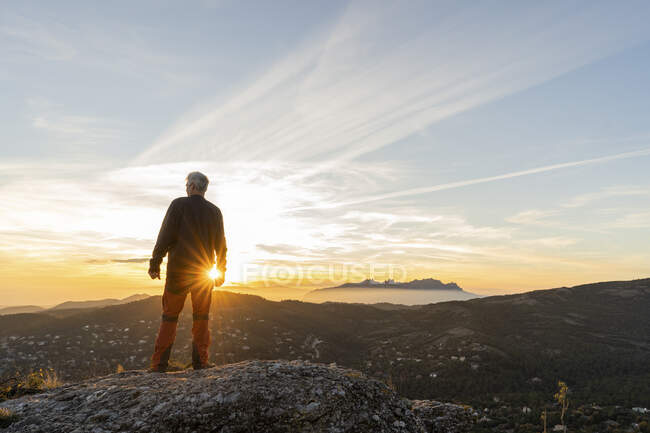 Man standing on cliff while looking at mountain — Stock Photo
