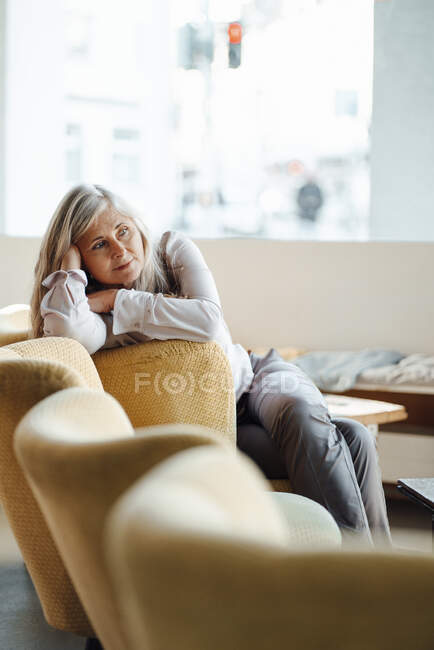 Donna appoggiata sulla sedia mentre seduta in caffetteria — Foto stock