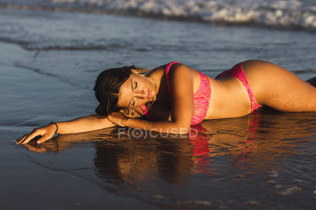 Mujer con bikini acostada en el agua al atardecer - foto de stock