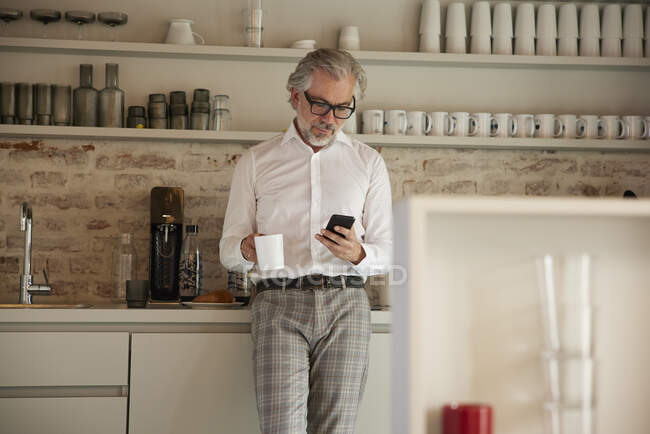 Бизнесмен, пользующийся мобильным телефоном во время кофе в кафетерии — стоковое фото
