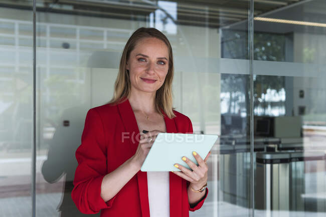 Female professional holding digital tablet in front of glass wall — Stock Photo