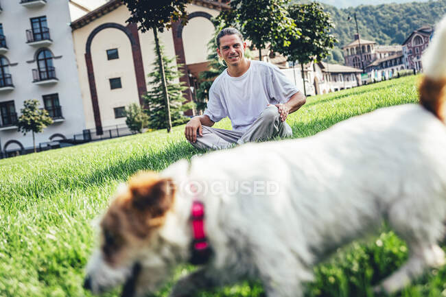 Metà uomo adulto guardando il cane mentre seduto sull'erba — Foto stock