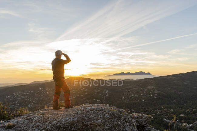 Hombre mayor mirando montañas durante el atardecer - foto de stock