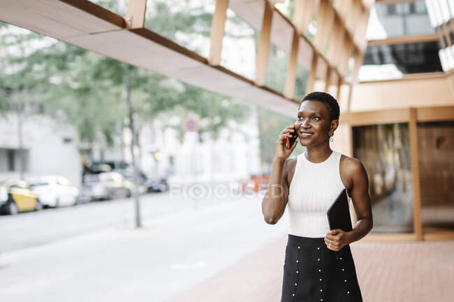 Усміхнена бізнес-леді тримає цифровий планшет під час розмови на смартфоні — стокове фото