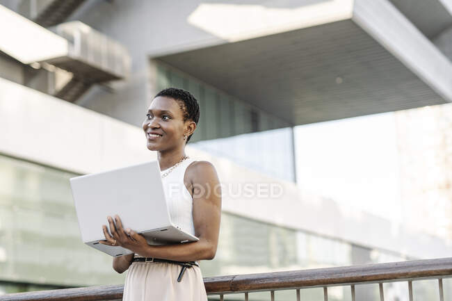 Женщина-фрилансер с ноутбуком, стоящим у ограждения — стоковое фото