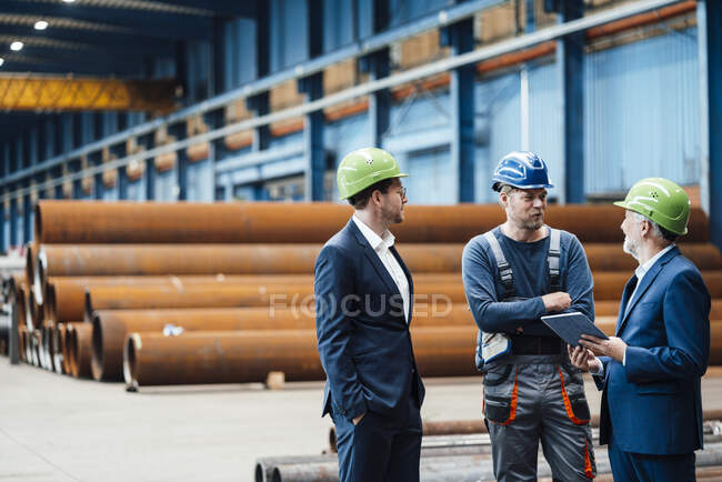 Les hommes d'affaires discutent avec le travailleur d'entrepôt dans l'usine — Photo de stock