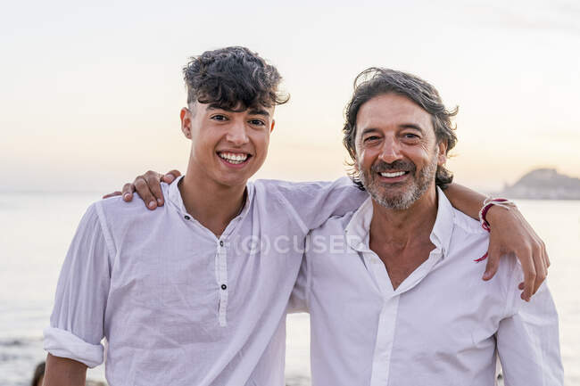 Счастливый взрослый мужчина с сыном на пляже во время заката — стоковое фото