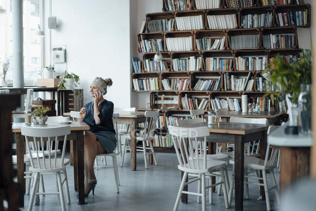 Donna d'affari che parla sul telefono cellulare mentre è seduto in un caffè — Foto stock
