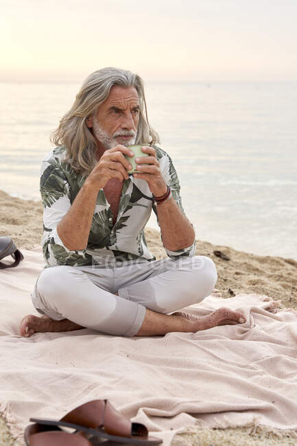 Мужчина со скрещенными ногами на пляже — стоковое фото