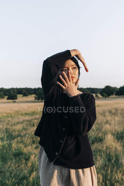 Young woman touching face while standing at park — Stock Photo