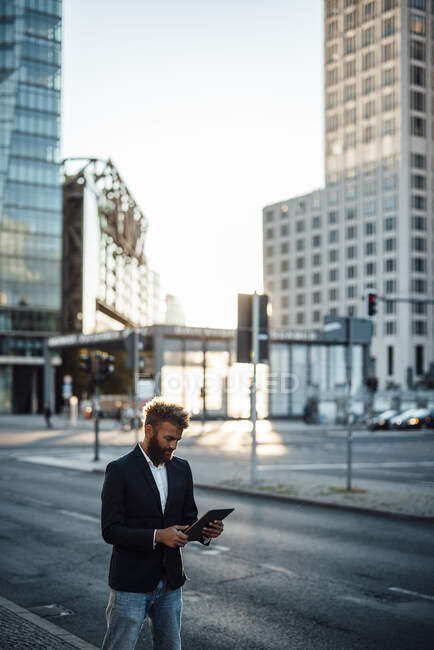Businessman in smart casual using digital tablet on street — Stock Photo